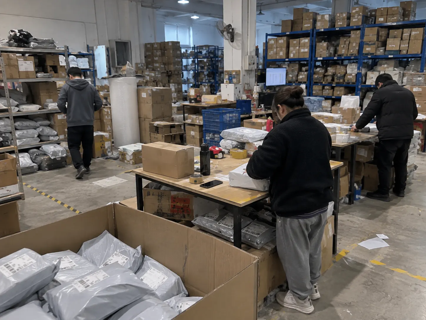 Stock on shelves and orders being packed into labelled mailers in a warehouse in China